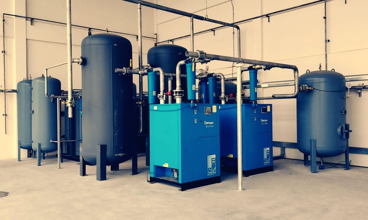 An air compressor standing on a garage floor beside coiled hose