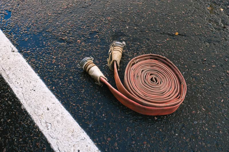 A red rubber air hose with brass fittings on a workbench