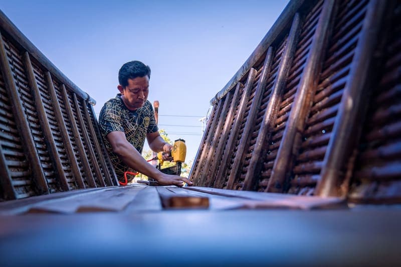 A carpenter driving fasteners into a wooden structure with a pneumatic nail gun