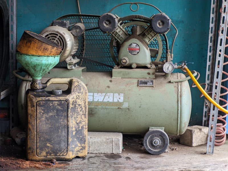 A compact quiet-series air compressor beside coiled air hose