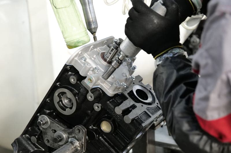 A compact nano-bodied air impact wrench held over an engine bay