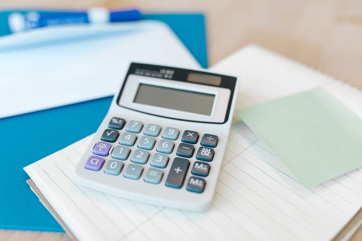 A notepad and calculator beside technical notes on a desk