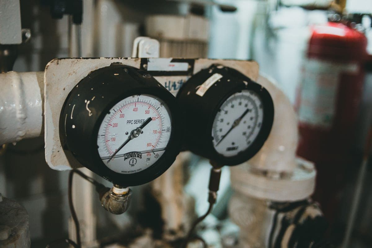A pressure gauge on a compressor manifold being inspected