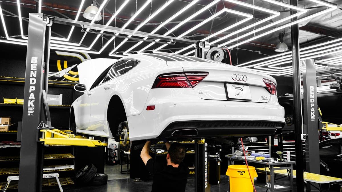The interior of an automotive repair shop with a vehicle on a lift