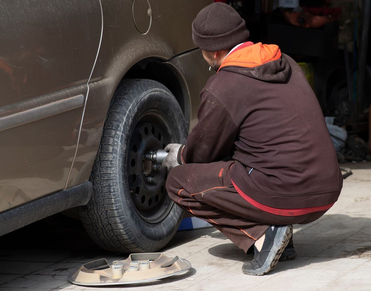 Changing a car wheel with tools laid out on the ground